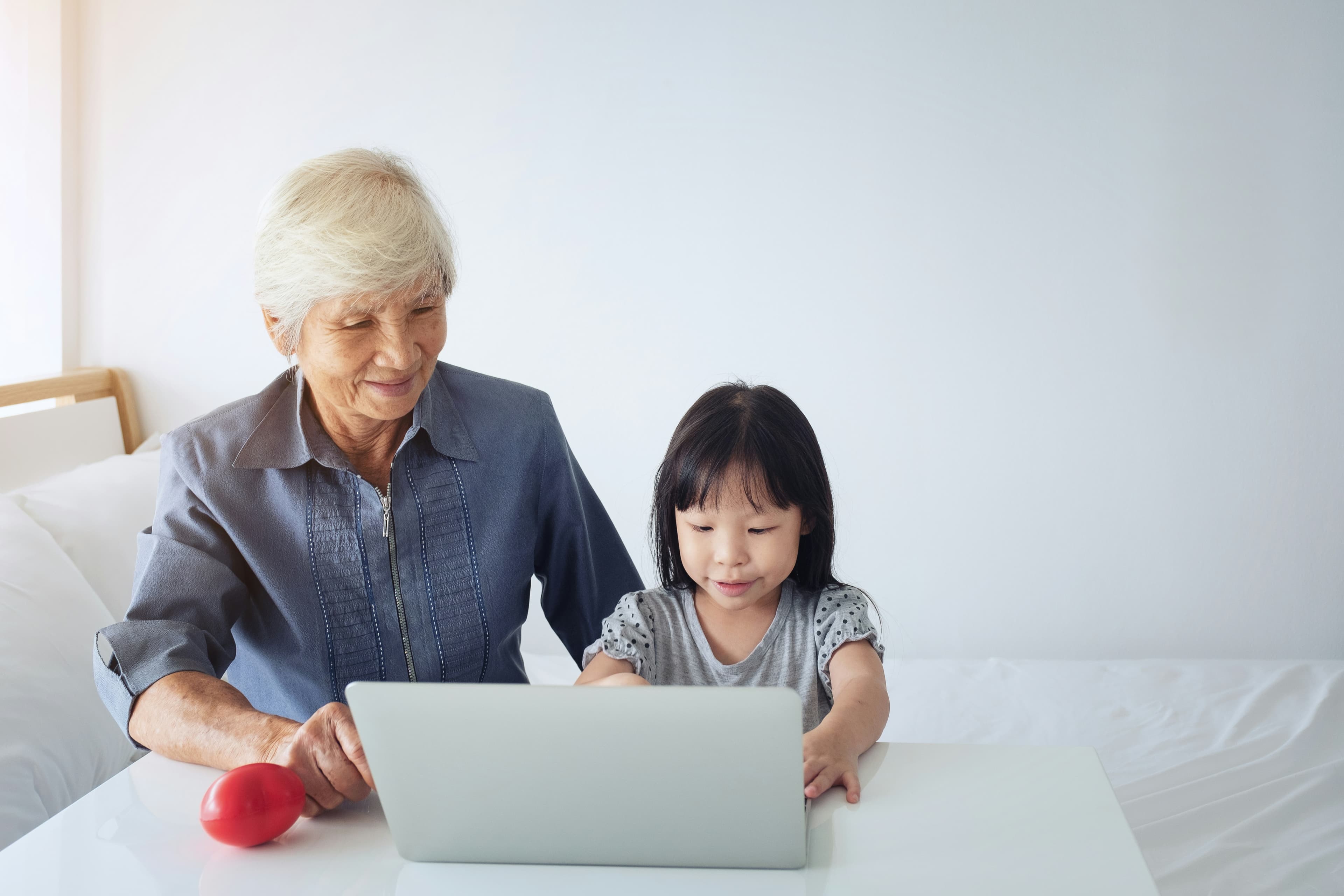 A caring child helping an elderly parent navigate a laptop, symbolizing the collaborative approach to digital security.